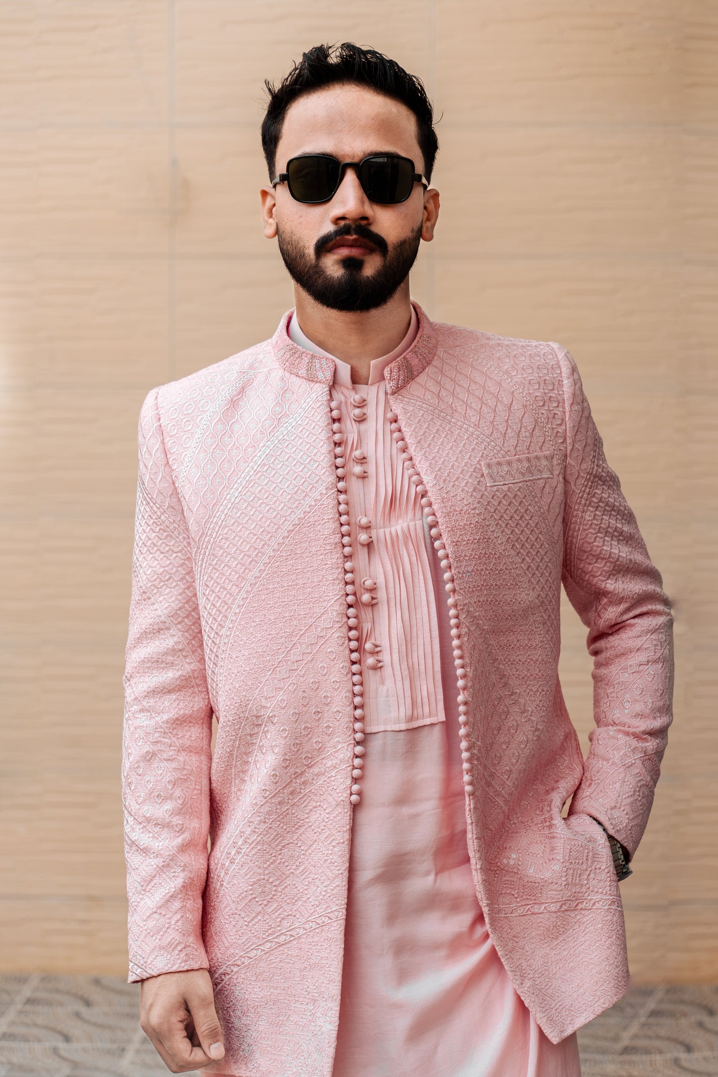 Pastel pink 3-piece prince coat set with textured sequence embroidery and pearl-button detailing on the front. Layered over a pleated pink kurta and matching straight trousers