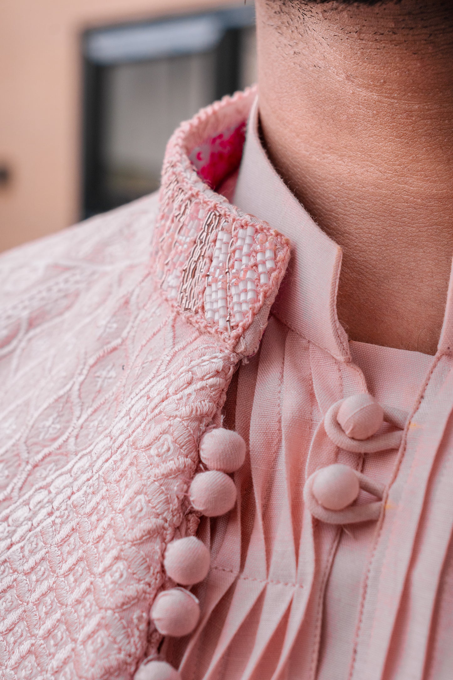 Pastel pink 3-piece prince coat set with textured sequence embroidery and pearl-button detailing on the front. Layered over a pleated pink kurta and matching straight trousers
