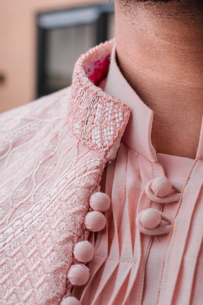 Pastel pink 3-piece prince coat set with textured sequence embroidery and pearl-button detailing on the front. Layered over a pleated pink kurta and matching straight trousers