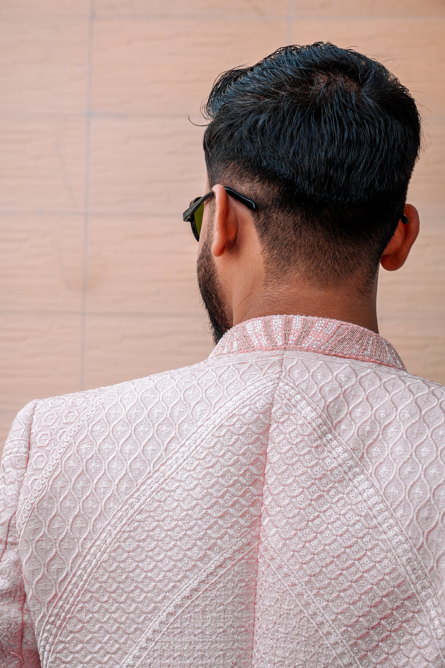 Pastel pink 3-piece prince coat set with textured sequence embroidery and pearl-button detailing on the front. Layered over a pleated pink kurta and matching straight trousers