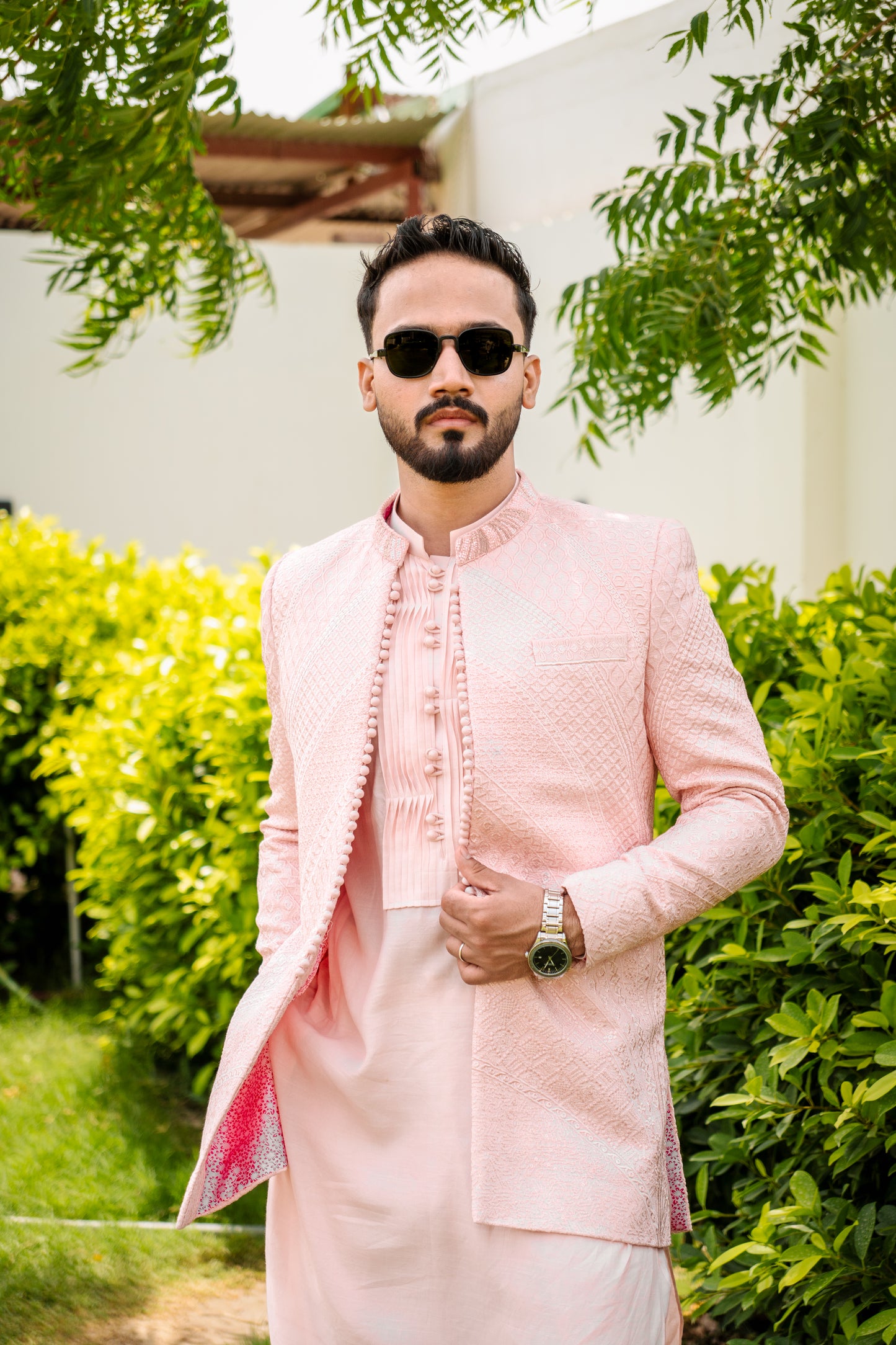 Pastel pink 3-piece prince coat set with textured sequence embroidery and pearl-button detailing on the front. Layered over a pleated pink kurta and matching straight trousers