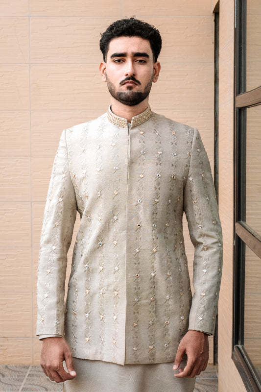Light sage/grey prince coat with vertical embroidery and mirror work all over. Band collar with subtle gold detailing. Paired with matching kurta pajama