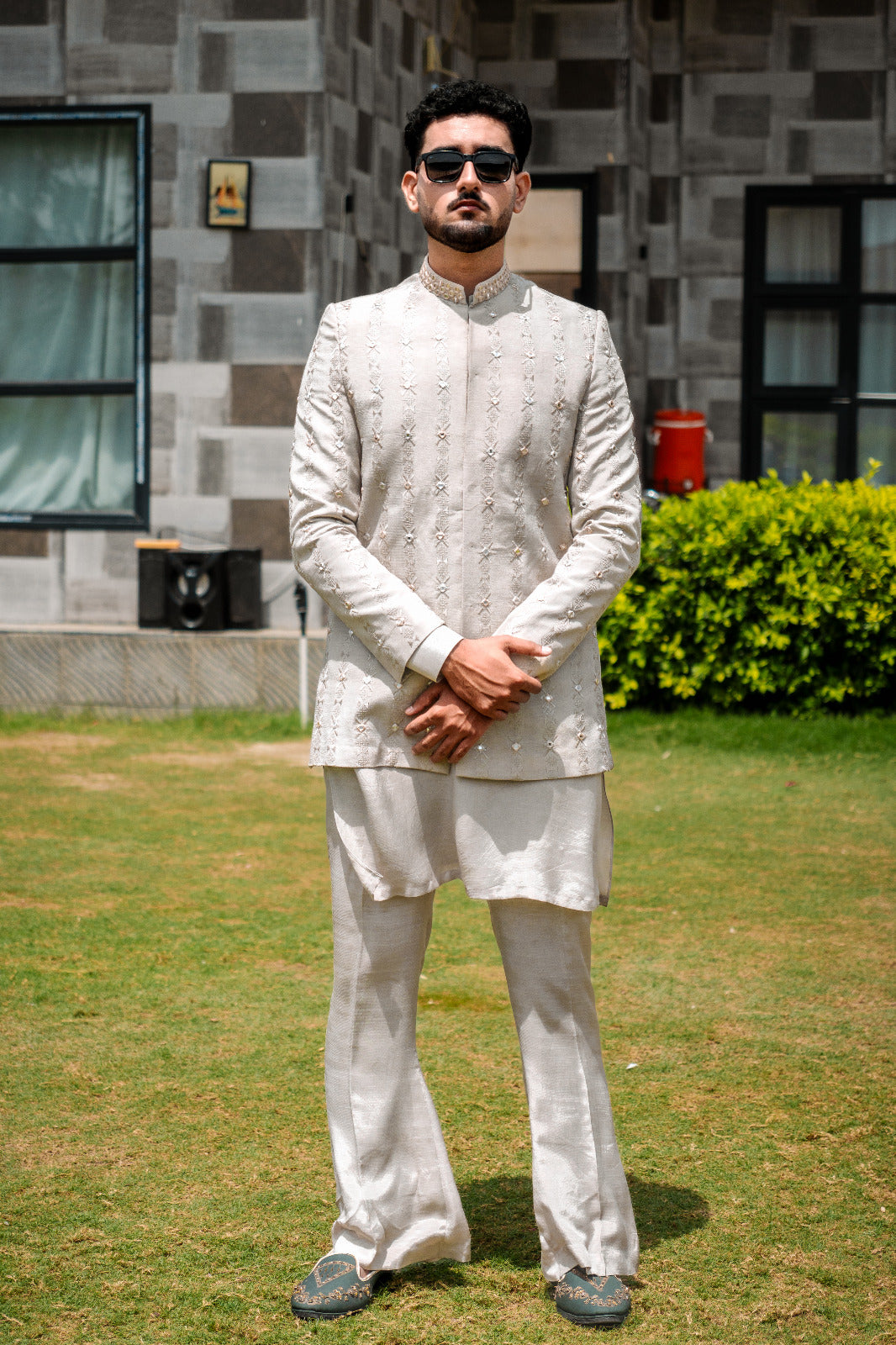 Light sage/grey prince coat with vertical embroidery and mirror work all over. Band collar with subtle gold detailing. Paired with matching kurta pajama